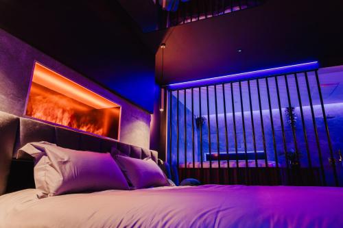 une chambre avec un grand lit avec un éclairage violet dans l'établissement Love Room Les Private Places - Lit King Size et Jacuzzi Privé, à Orléans
