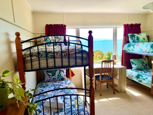 a bedroom with bunk beds and a table and a window at Family and pet friendly with stunning seaviews in Nelson