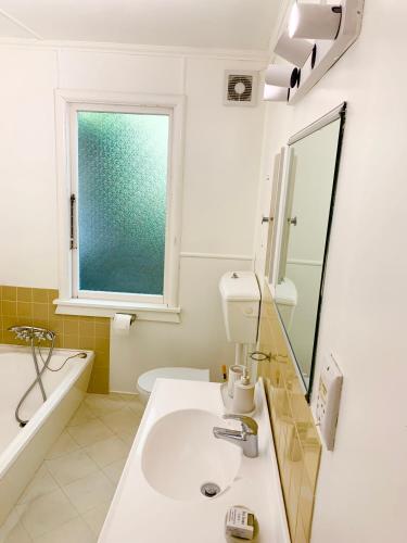 a bathroom with a sink and a mirror and a tub at Family and pet friendly with stunning seaviews in Nelson