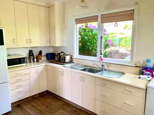 a white kitchen with a sink and a window at Family and pet friendly with stunning seaviews in Nelson