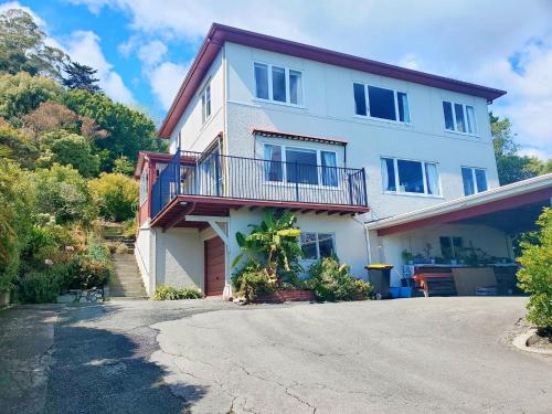 a white house with a balcony and a driveway at Family and pet friendly with stunning seaviews in Nelson