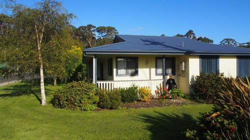 a man standing in front of a house at Strahan Retreat Holiday Park in Strahan