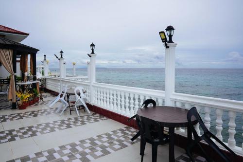 a balcony with a table and chairs and the ocean at RedDoorz Plus at Billy's Resort Oslob in Oslob