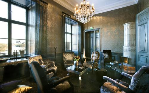 a living room with a chandelier and a table and chairs at Ulfsunda Slott in Stockholm