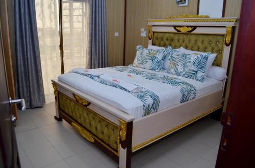 a bed with blue and white sheets and pillows at Résidence Le Sommet Douala in Douala
