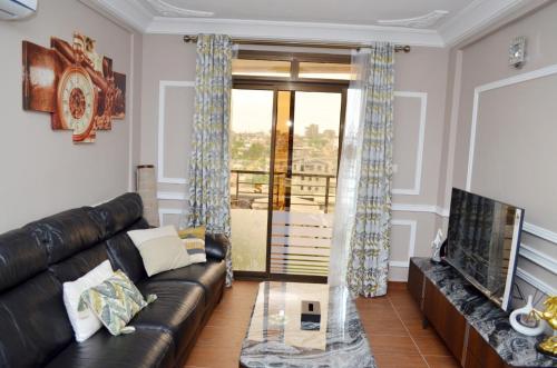 a living room with a leather couch and a television at Résidence Le Sommet Douala in Douala