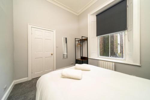 a bedroom with a white bed with a window at Lochside Apartments, Apt B in Montrose