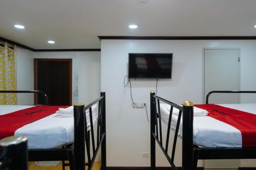 two beds in a room with a tv on the wall at RedDoorz Plus at Billy's Resort Oslob in Oslob