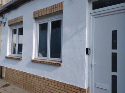 a white house with two windows and a door at Maison de ville in Bourbourg