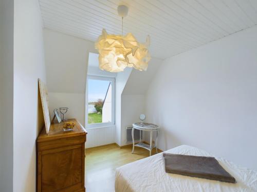 une chambre avec un lit et un lustre dans l'établissement Maison pour 5 - 50m du front de mer, à Penmarcʼh