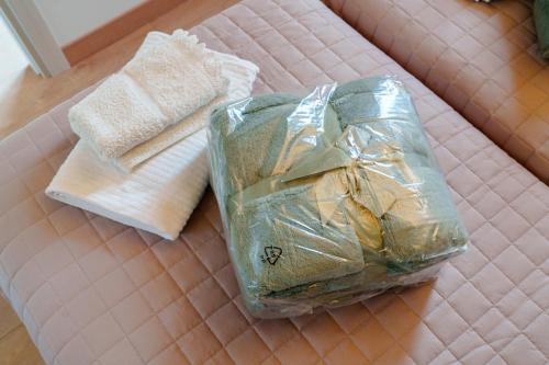 a plastic bag and two towels on a bed at Sarca Lodge Val Rendena in Dare