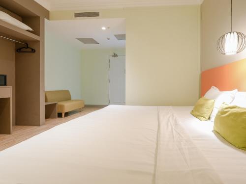 a bedroom with a large white bed with yellow pillows at A Hotel Joo Chiat in Singapore