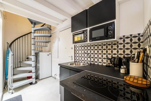 une cuisine avec un comptoir noir et un four micro-ondes dans l'établissement Jolie duplex avec patio, à Nice