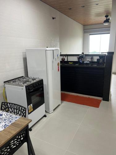 a kitchen with a stove and a white refrigerator at Moradas de Ibicuí - Apartamentos com vista para o mar in Mangaratiba