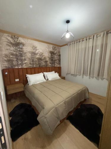 a bedroom with a bed with a painting on the wall at 3Mozaiket Voskopoje in Voskopojë