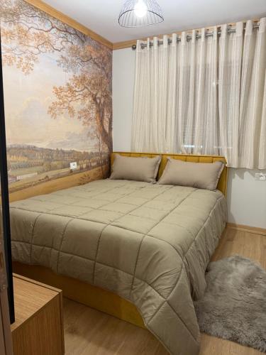 a bedroom with a large bed with a painting on the wall at 3Mozaiket Voskopoje in Voskopojë