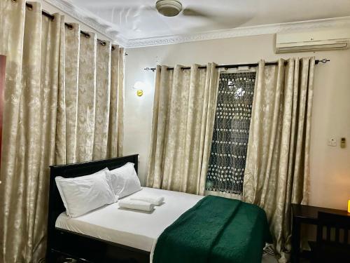 a bedroom with a bed and a window with curtains at Casazuri Homestay in Dar es Salaam