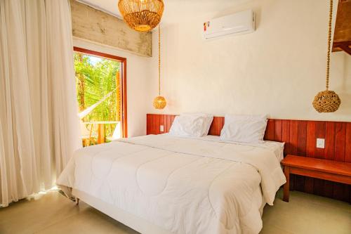 Un dormitorio con una gran cama blanca con ventana. en Santa Maria Inn, en São Miguel do Gostoso