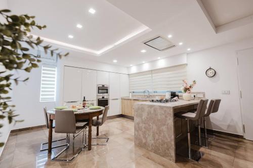 a kitchen with white walls and a table and chairs at Dolmen Court Qawra fl13 w shared pool! by Homely in St. Paul's Bay
