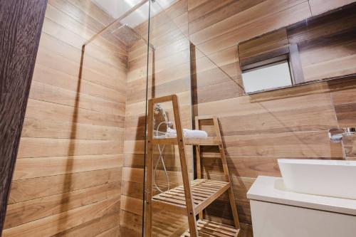 a bathroom with a shower with a wooden wall at Dolmen Court Qawra fl13 w shared pool! by Homely in St. Paul's Bay