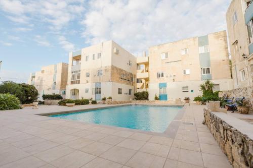 a swimming pool in front of a building at Dolmen Court Qawra fl13 w shared pool! by Homely in St. Paul's Bay