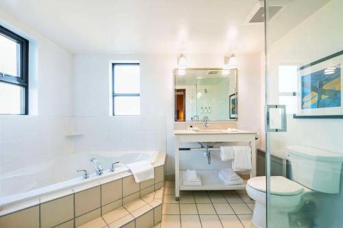 a bathroom with a tub and a toilet and a sink at Grand Park Hotel Vancouver Airport, an Ascend Collection Hotel in Richmond