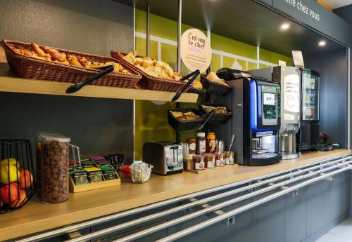 a coffee shop with a counter with bread and food at B&B HOTEL Nancy Frouard in Frouard
