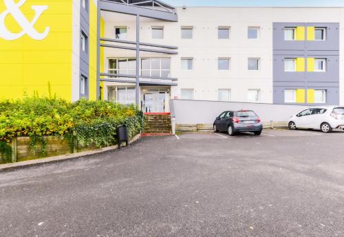 a parking lot with two cars parked in front of a building at B&B HOTEL Nancy Frouard in Frouard