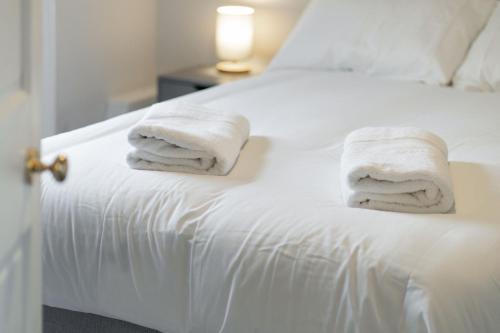 a white bed with towels on top of it at Lochside Apartments, Apt C in Montrose