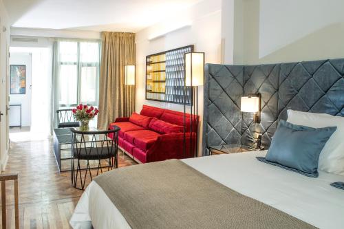 Hotel Luciano K في سانتياغو: غرفة فندق بسرير واريكة حمراء