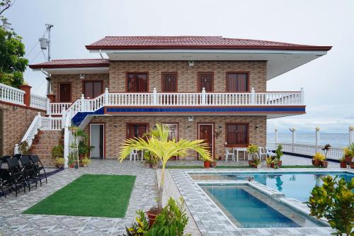 a house with a swimming pool in front of it at RedDoorz Plus at Billy's Resort Oslob in Oslob