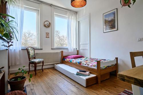 une chambre avec un lit, une chaise et des fenêtres dans l'établissement La Briqueterie - Les Demeures d'Adrien, à Lille