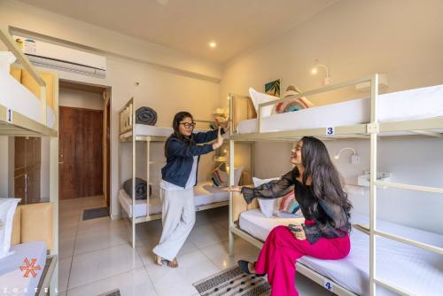 a man and woman standing in a room with bunk beds at Zostel Rishikesh, Tapovan in Rishīkesh