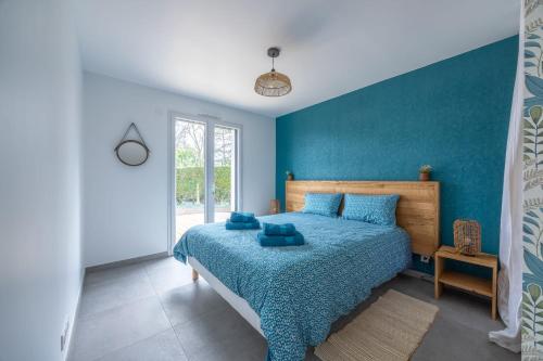 a bedroom with a bed with a blue wall at Maison neuve parking 6 pers Jardin Terrasse Wifi in Banneville-sur-Ajon