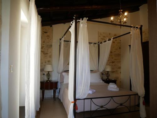 a bedroom with a canopy bed with white curtains at Christina's Villa with sea view in Daratso