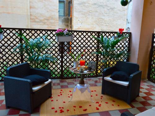 a patio with two chairs and a table and a fence at Alba Camere in Palermo