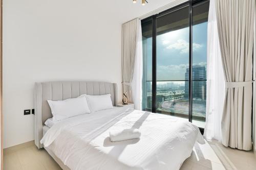 a bedroom with a white bed and a large window at Savis Home - Enjoy the City Skyline View 1BR in Binghatti Venus JVC in Dubai