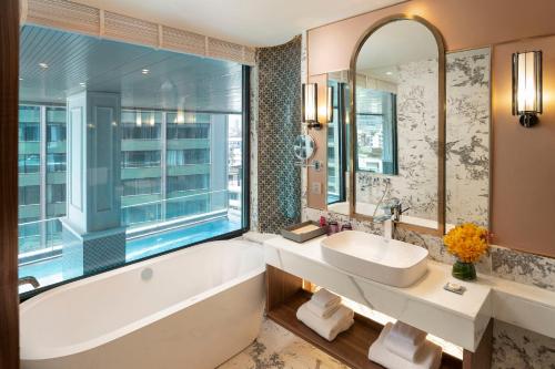 a bathroom with a tub and a sink and a window at Valia Hotel Bangkok in Bangkok