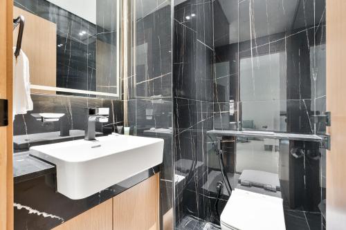 a black tiled bathroom with a sink and a toilet at Savis Home - Enjoy the City Skyline View 1BR in Binghatti Venus JVC in Dubai