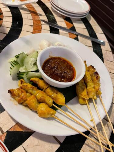a plate of food with meat and a bowl of sauce at Holiday Villa Resort & Beachclub Langkawi in Pantai Cenang