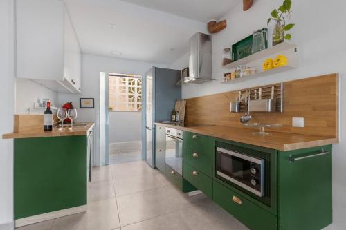 a kitchen with green cabinets and wooden counter tops at La Casa de las Hesperides in Morro del Jable