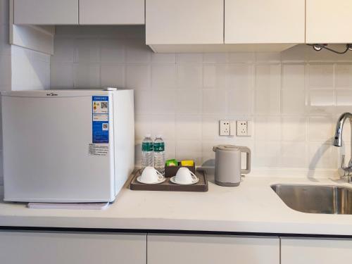 a kitchen counter with a sink and a white refrigerator at 浮生慢遇酒店 in Dali Airport