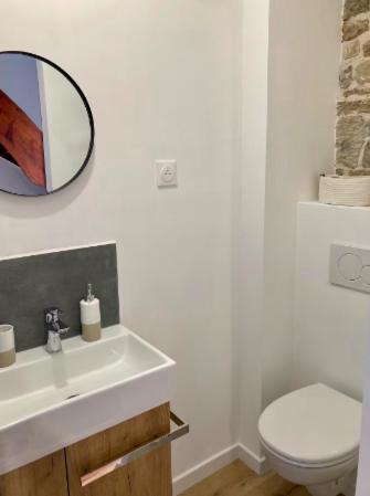 une salle de bain avec un lavabo, des toilettes et un miroir dans l'établissement Gîte rénové à Ravenoville, à Sainte-Mère-Église