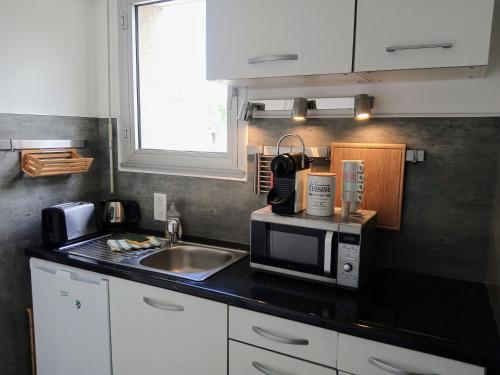 une cuisine avec un évier et un micro-ondes dans l'établissement L'Urban centre ville linge café thé inclus, à Vannes