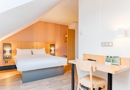 a bedroom with a bed and a desk and a table at B&B HOTEL Poitiers 3 Futuroscope in Chasseneuil-du-Poitou