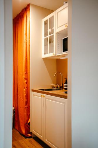 une cuisine avec des armoires blanches et un évier dans l'établissement Magnifique Studio, Bord de mer, Sur la plage, à Pleudihen-sur-Rance