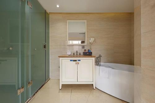a bathroom with a tub and a sink and a mirror at 凯旋龙酒店广州区庄地铁站店 广交会期间免费穿梭巴士 in Guangzhou