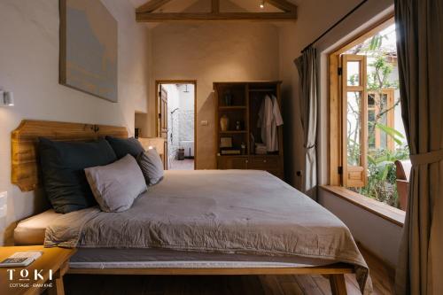 a bedroom with a bed and a window at TOKI Cottage Đam Khê in Vũ Lâm