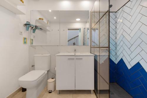 a white bathroom with a toilet and a sink at La Casa de las Hesperides in Morro del Jable