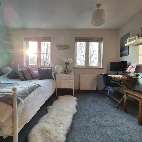 a bedroom with a bed and a desk with a computer at Pebble Cottage in Hunstanton